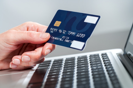 Online-Sofortüberweisung als Zahlungsmittel zumutbar Eine Hand hält eine Kreditkarte vor einem Computer