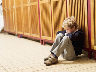 Trauriger Junge Junge sitzt vor Schulspind