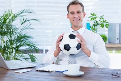 Fußball am Arbeitsplatz Mann hält am Büroarbeitsplatz einen Fußball in den Händen