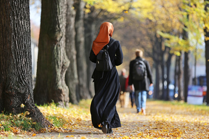 Muslima Frau mit Kopftuch auf Allee mit Herbstlauf
