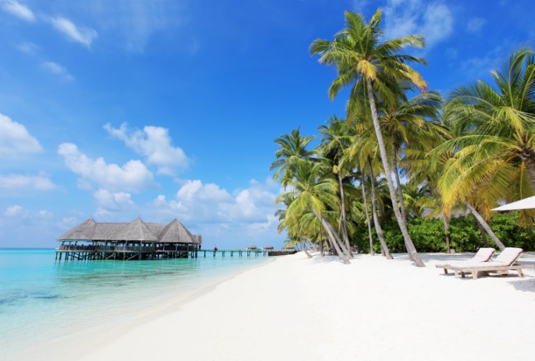 Tropischer Strand mit Hütten auf dem Wasser.